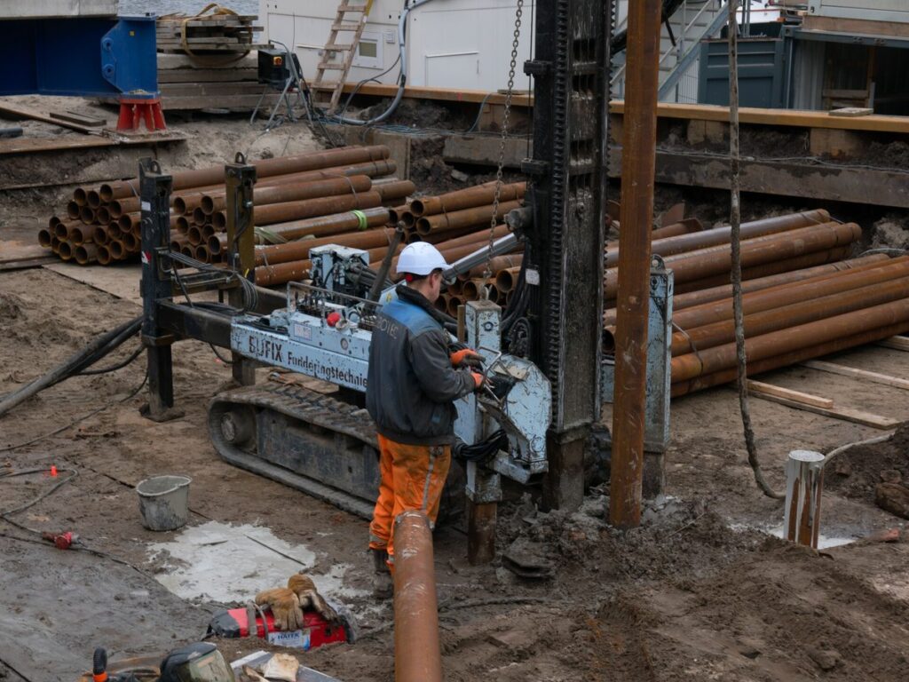 2025 - free image of a building worker at a construction site - drilling rusty piles in the peat soil for the